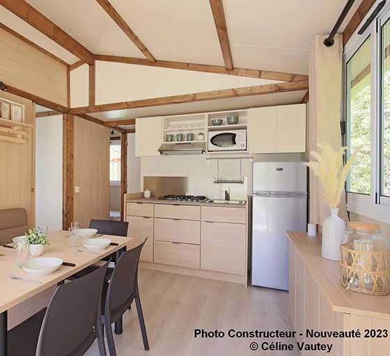 Equipped kitchen and living room of the chalet cottage 25 m² 2 bedrooms, to rent at the Campsite Les Ballastières in Champagney