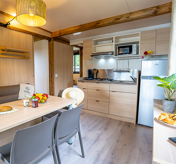 Equipped kitchen and living room of the chalet cottage 25 m² 2 bedrooms, to rent at the Campsite Les Ballastières in Champagney