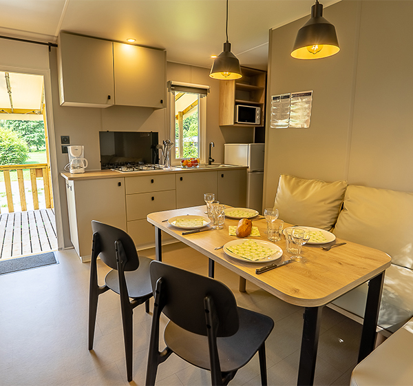 The interior of the 2-bedroom Premium mobile home with fully equipped kitchen and living room, for rent at the Campsite Les Ballastières in Haute-Saône