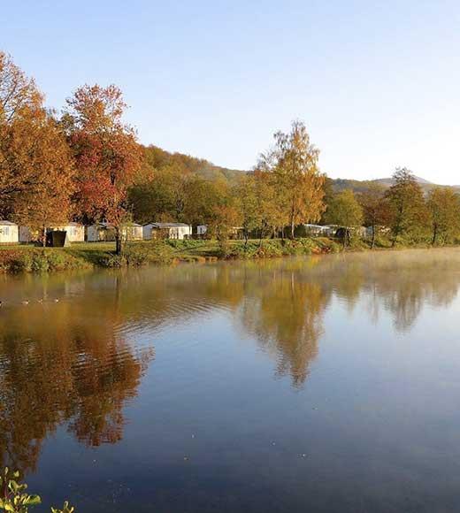 View of the rentals of the Campsite Les Ballastières in Haute-Saône by the water