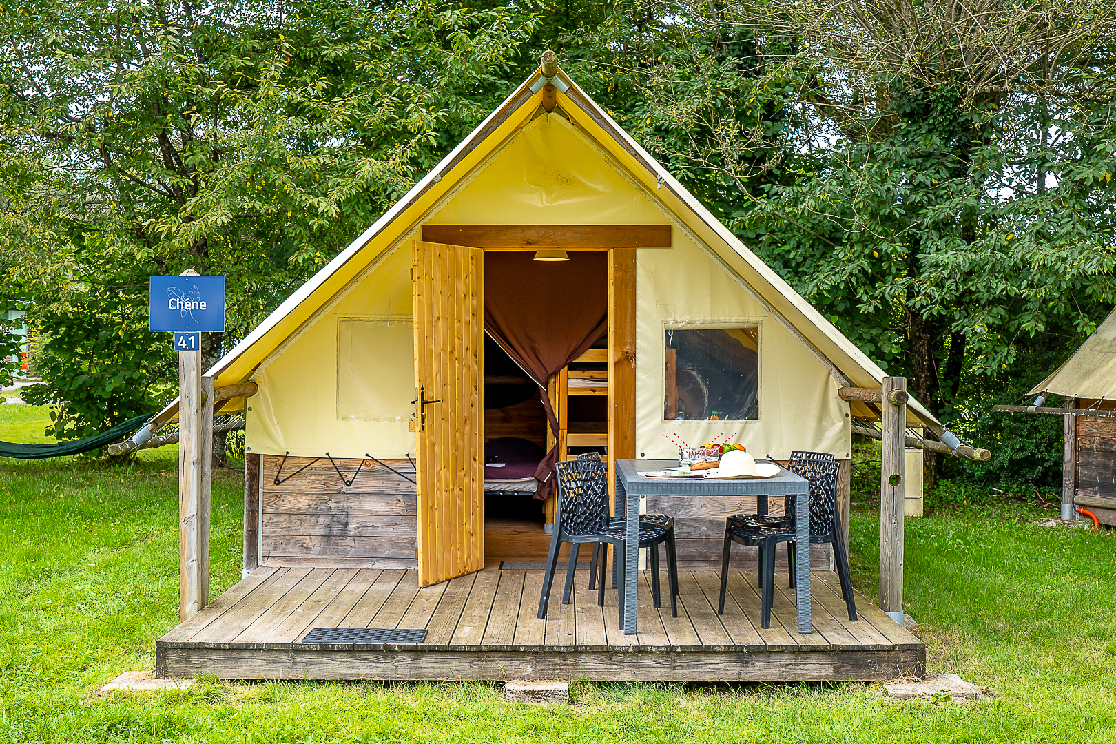 Tente glamping avec terrasse, nature environnante.