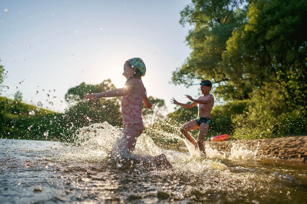 Enfants jouant dans l'eau d'une rivière en été.