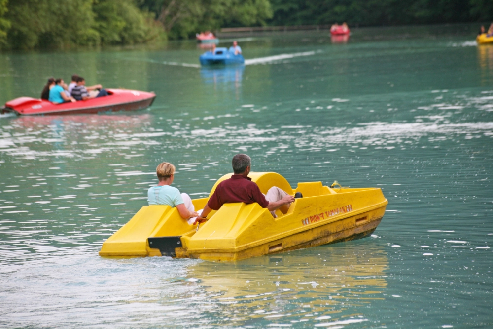 Personnes sur pédalos jaunes sur un lac.
