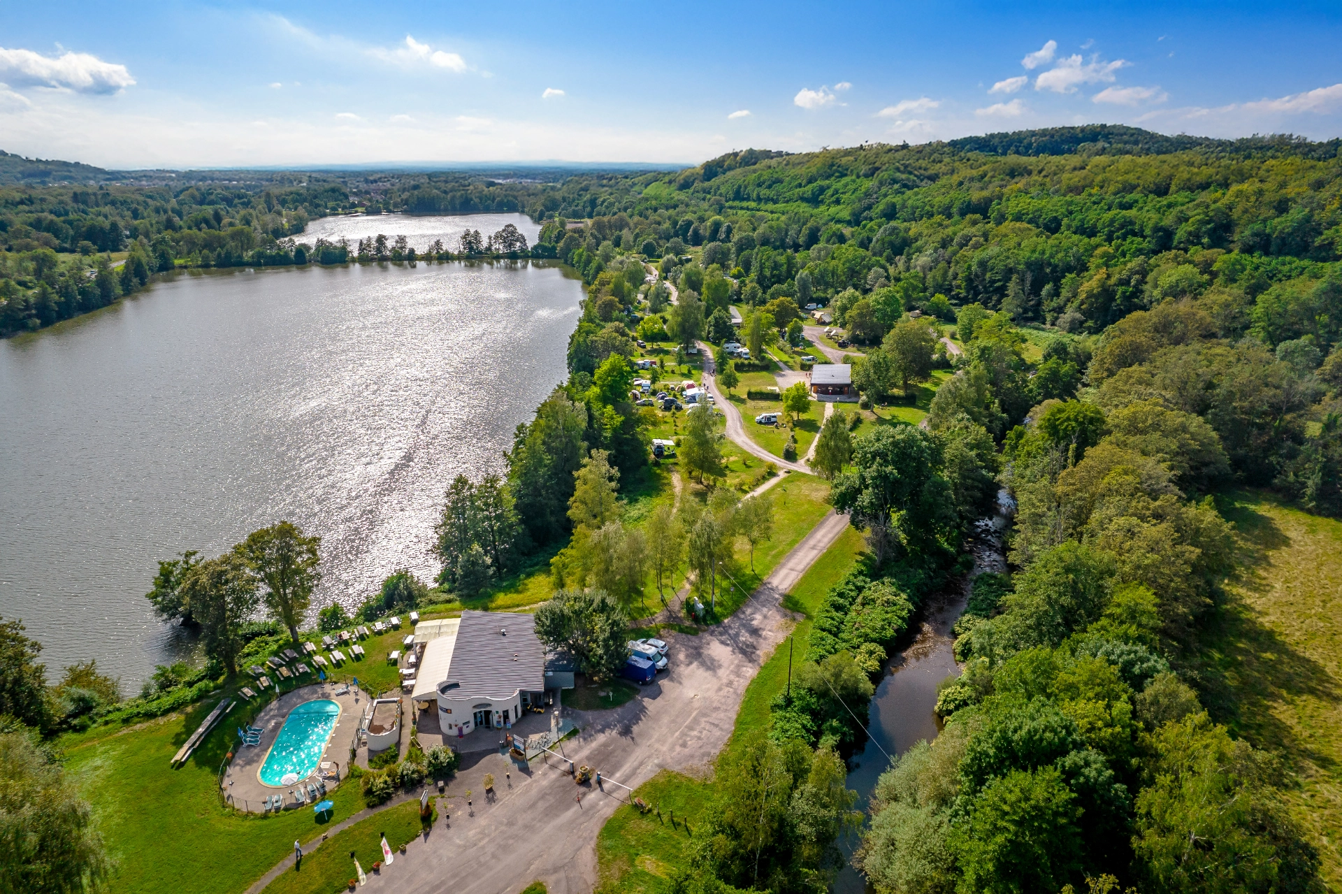 Vue aérienne de camping près d'un lac et forêt.