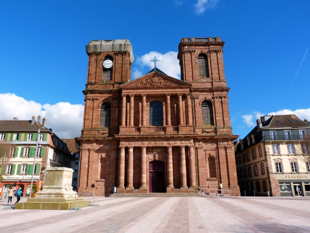 Cathédrale historique en pierre rouge, ciel bleu clair.