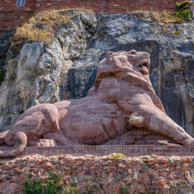 Lion de Belfort en pierre devant la falaise.
