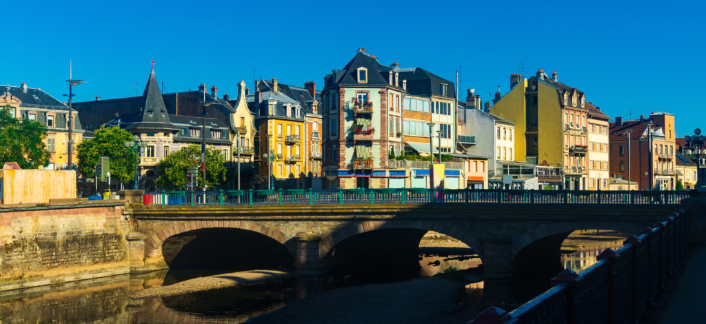 Bâtiments colorés et pont sur une rivière française.