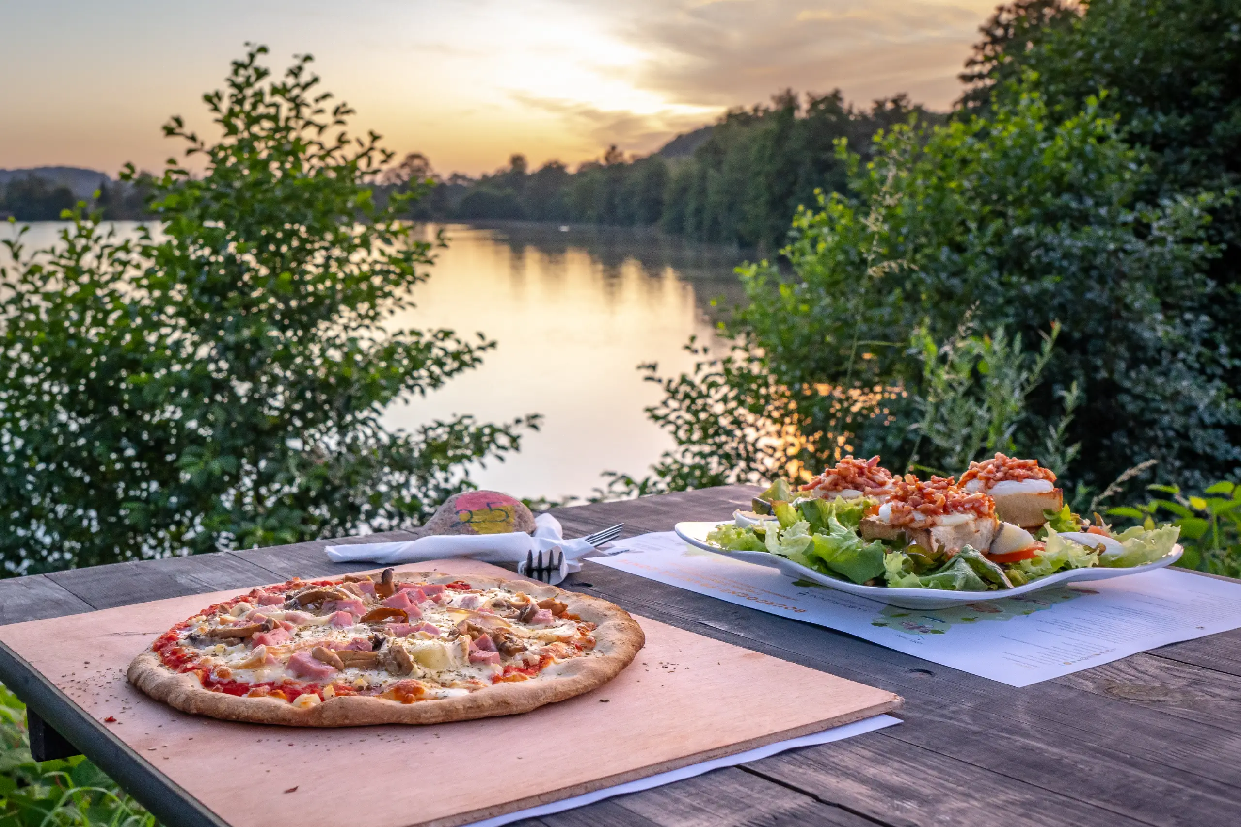 Pizza et salade sur table en bord de lac.