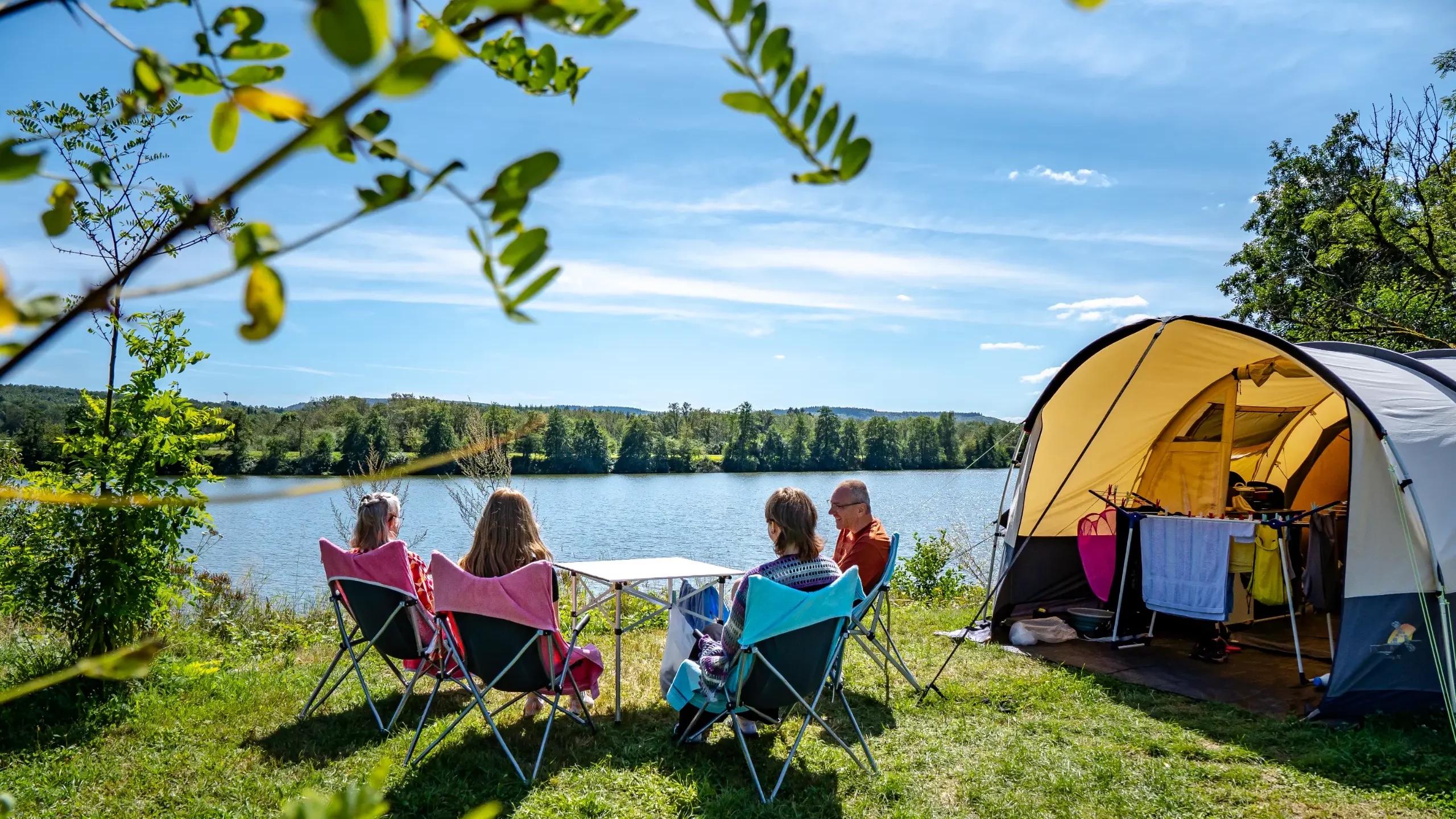 Gezinscamping bij een meer, zonnige dag.