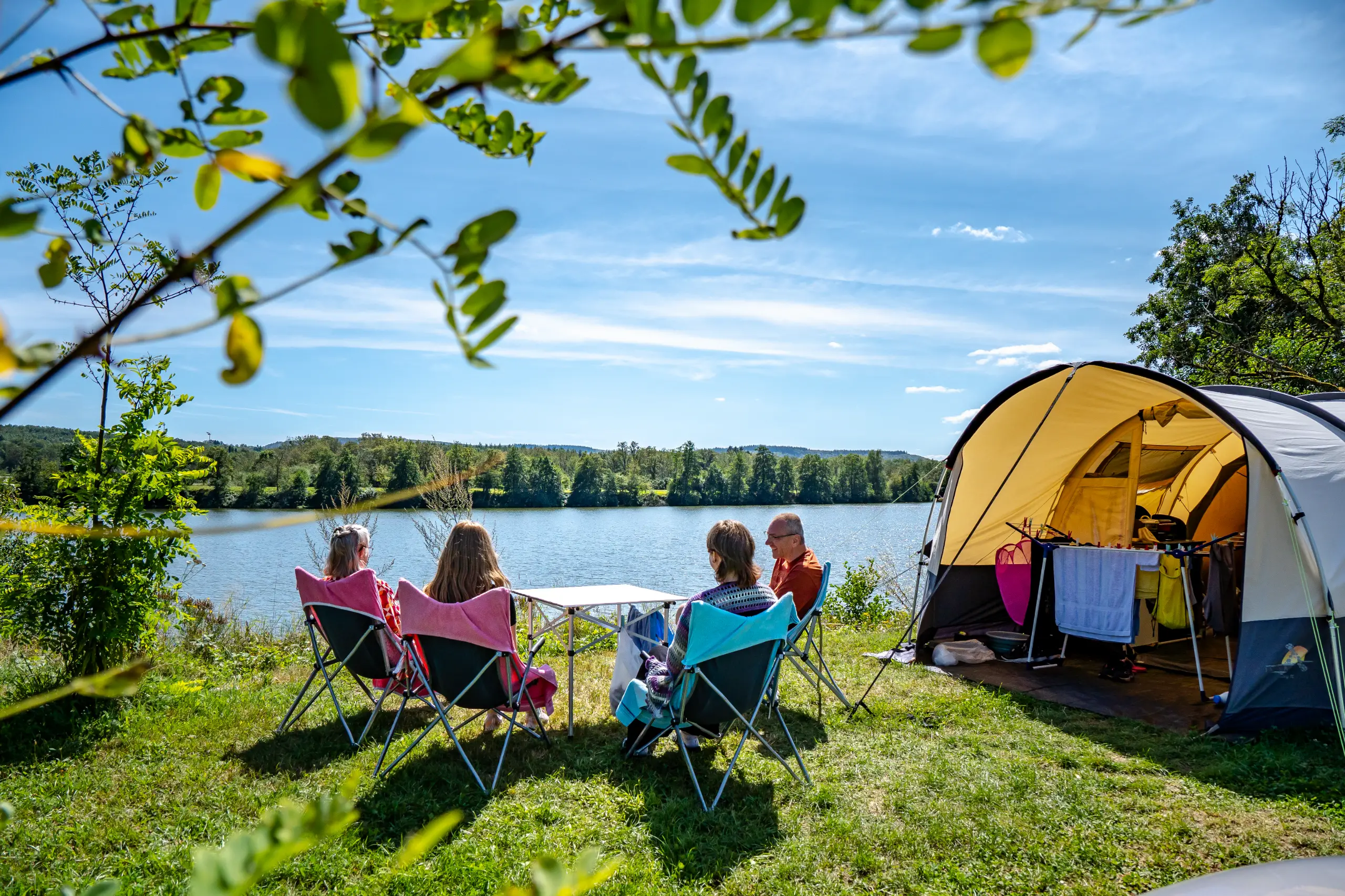 Gezinscamping bij een meer, zonnige dag.
