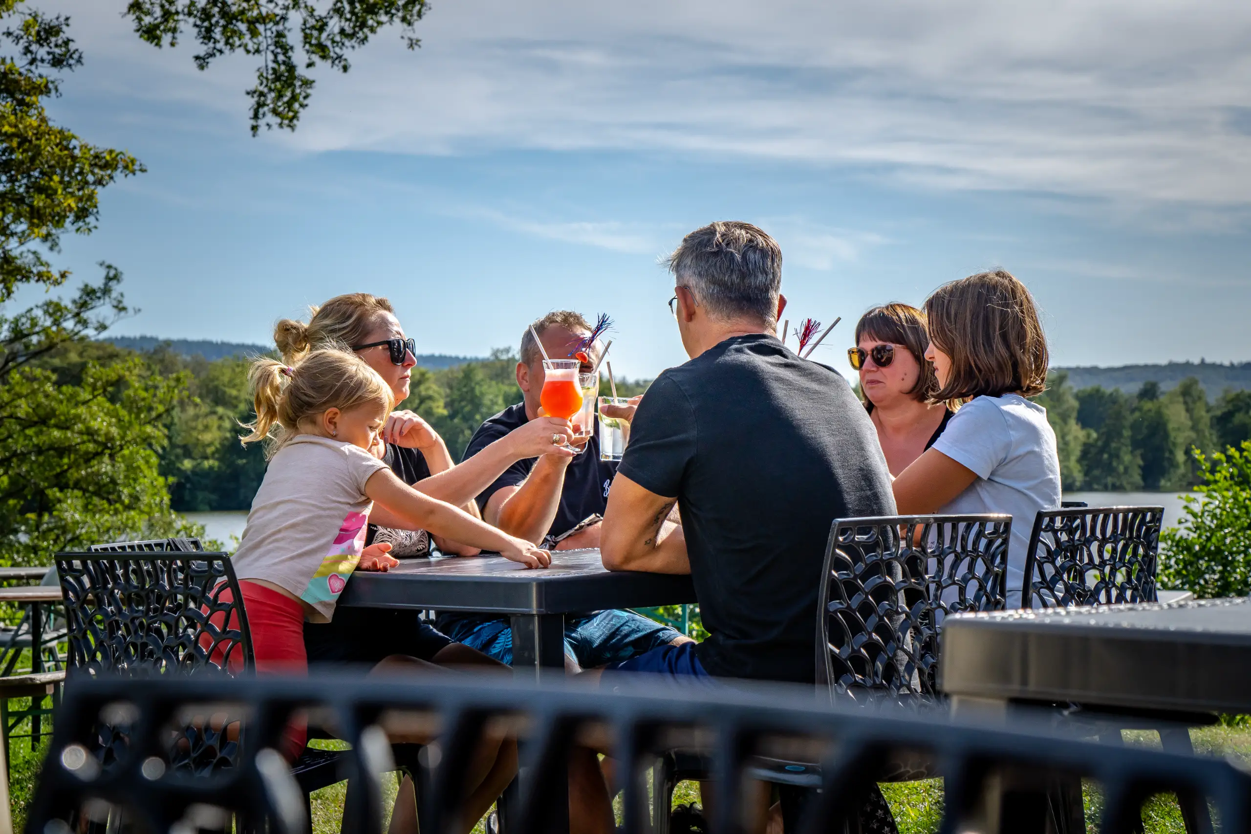 Famille partageant un repas en extérieur, campagne.