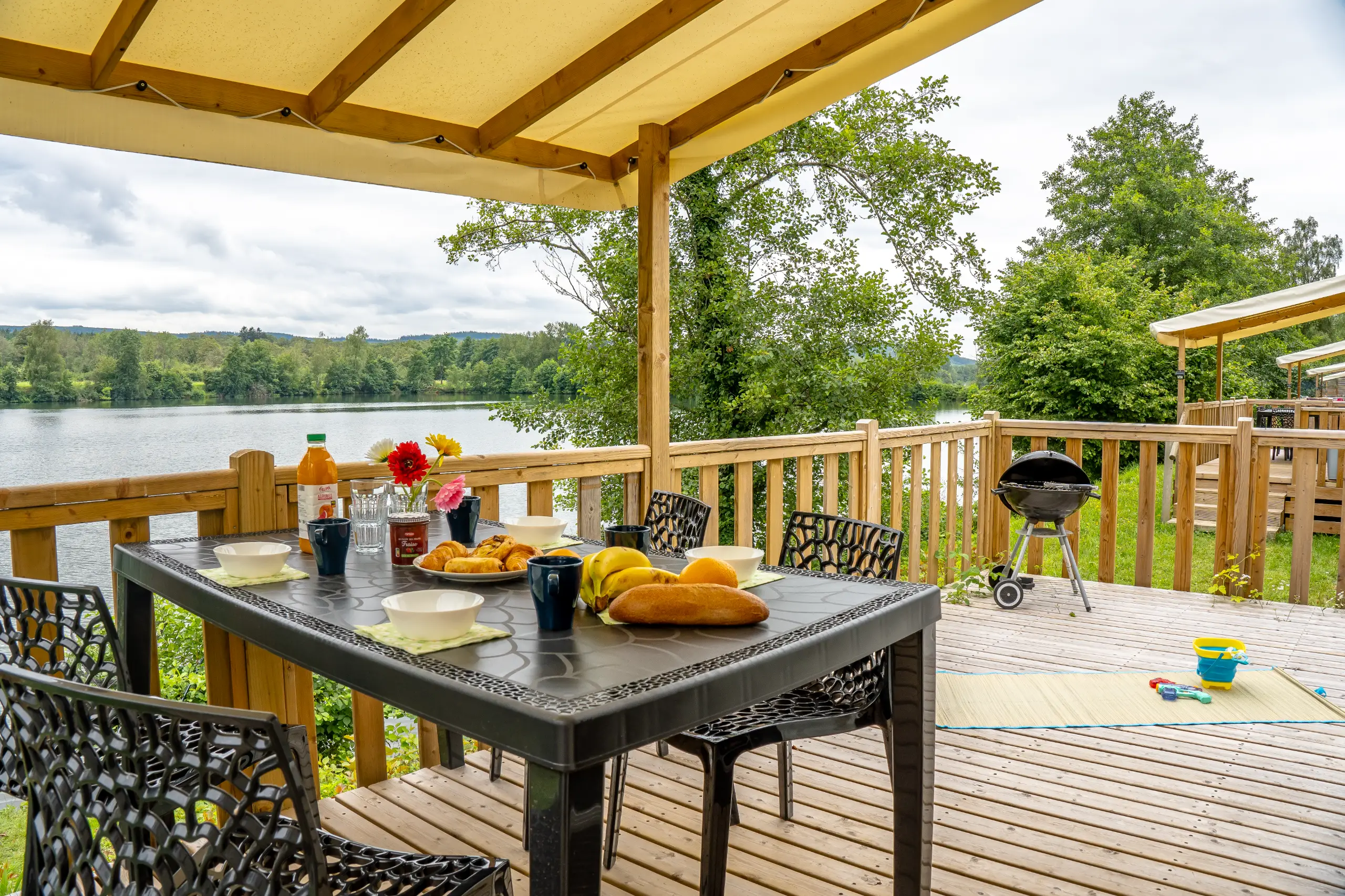 Terrasse en bois avec vue sur lac et petit-déjeuner.