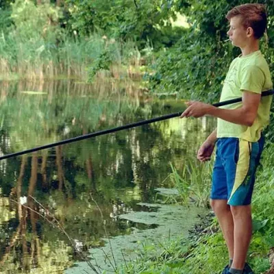 Garçon pêche au bord d'un étang paisible.