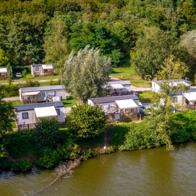Vue aérienne des chalets près d'un lac, nature verdoyante.