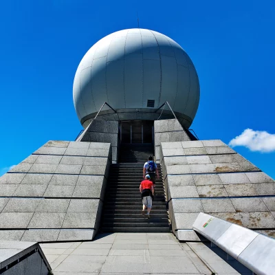 Deux personnes montent vers un radar sphérique.