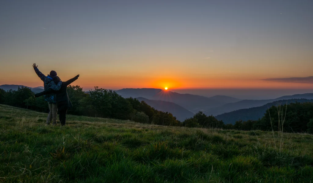 Coucher de soleil sur montagne, deux personnes s'embrassent.
