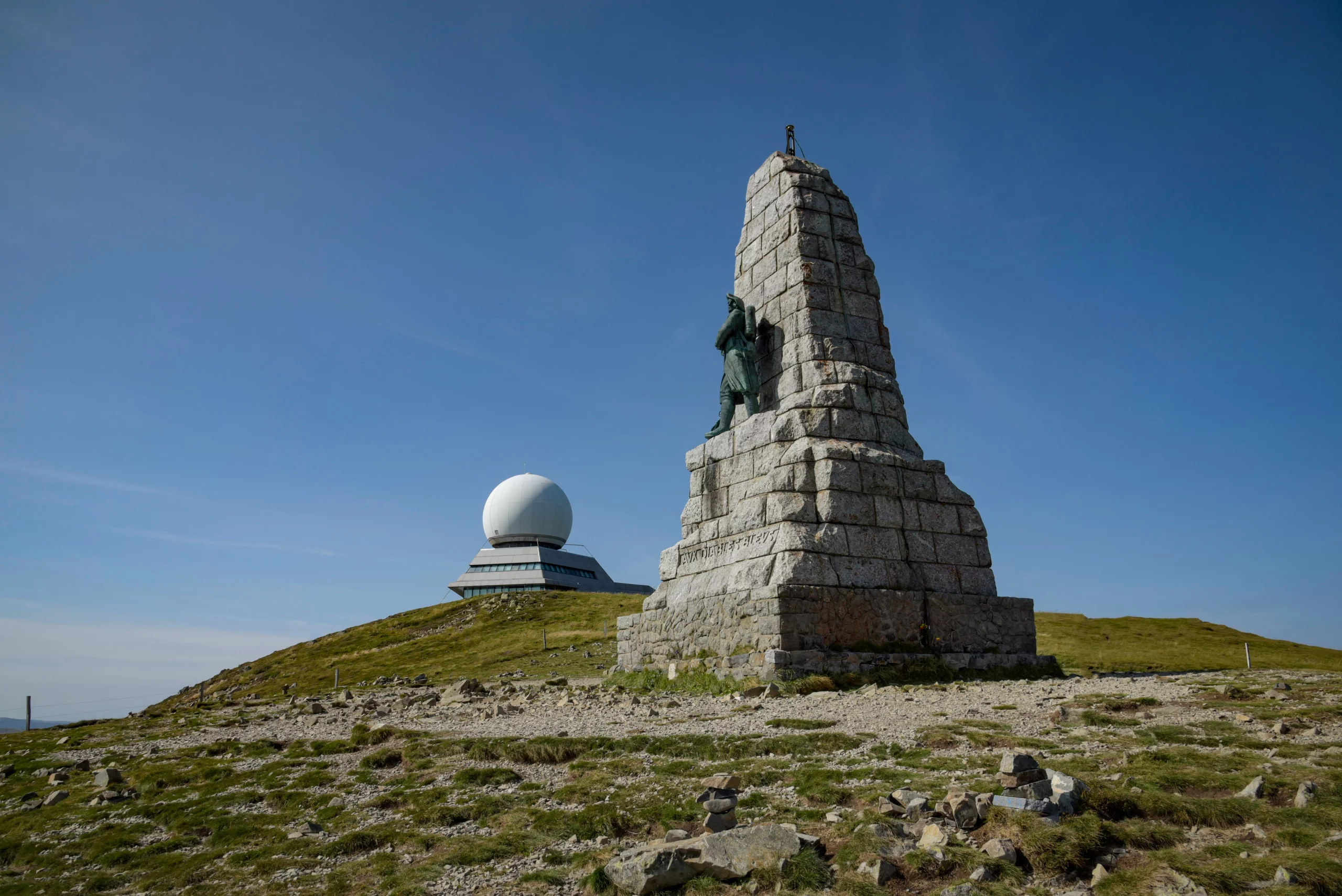 Monument et radar sur colline ensoleillée.