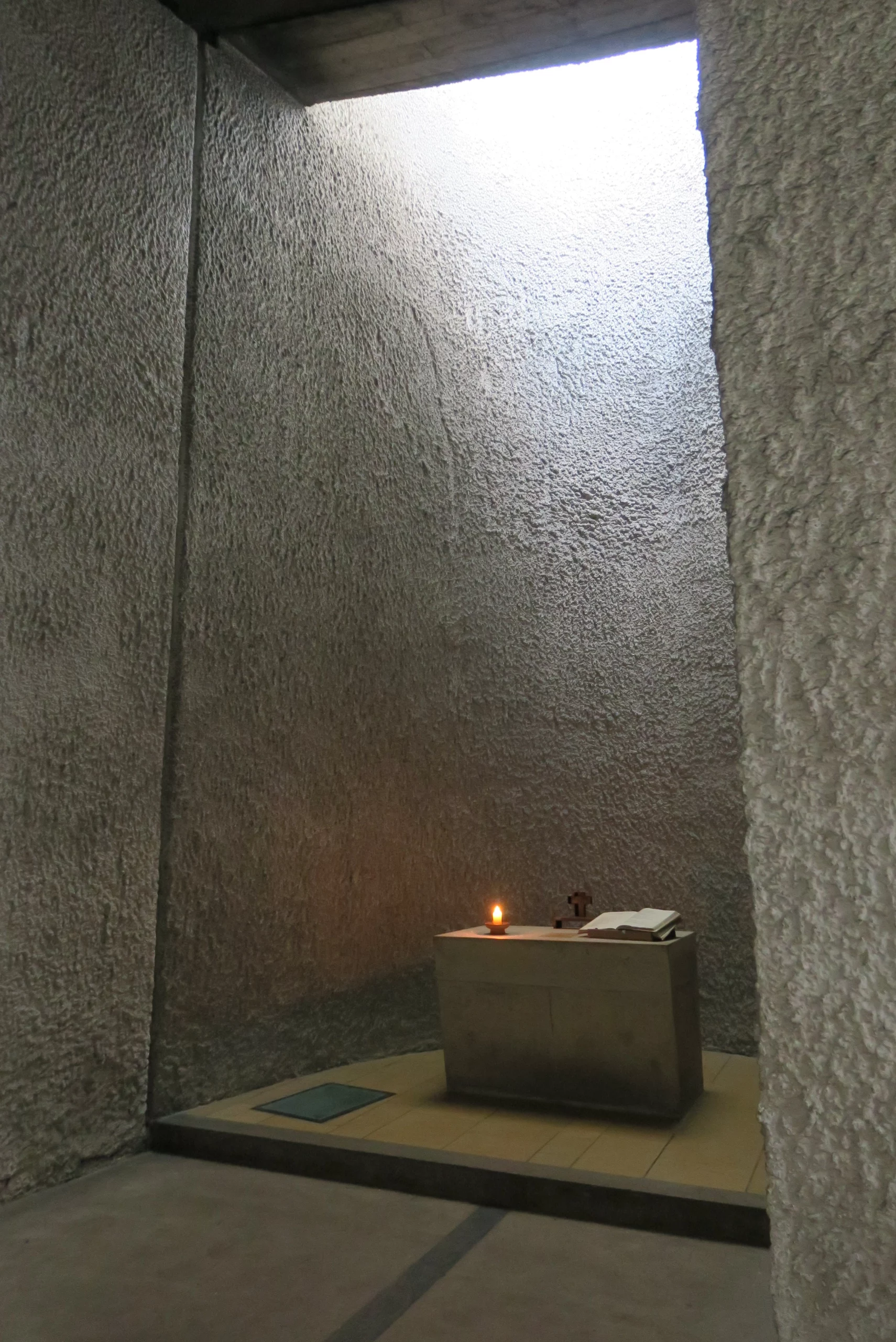 Petit autel en pierre avec bougie allumée.