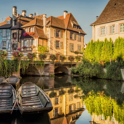 Maisons alsaciennes et barques sur canal pittoresque.