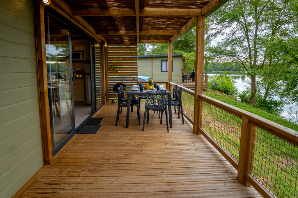 Wooden porch with table overlooking lake and trees.