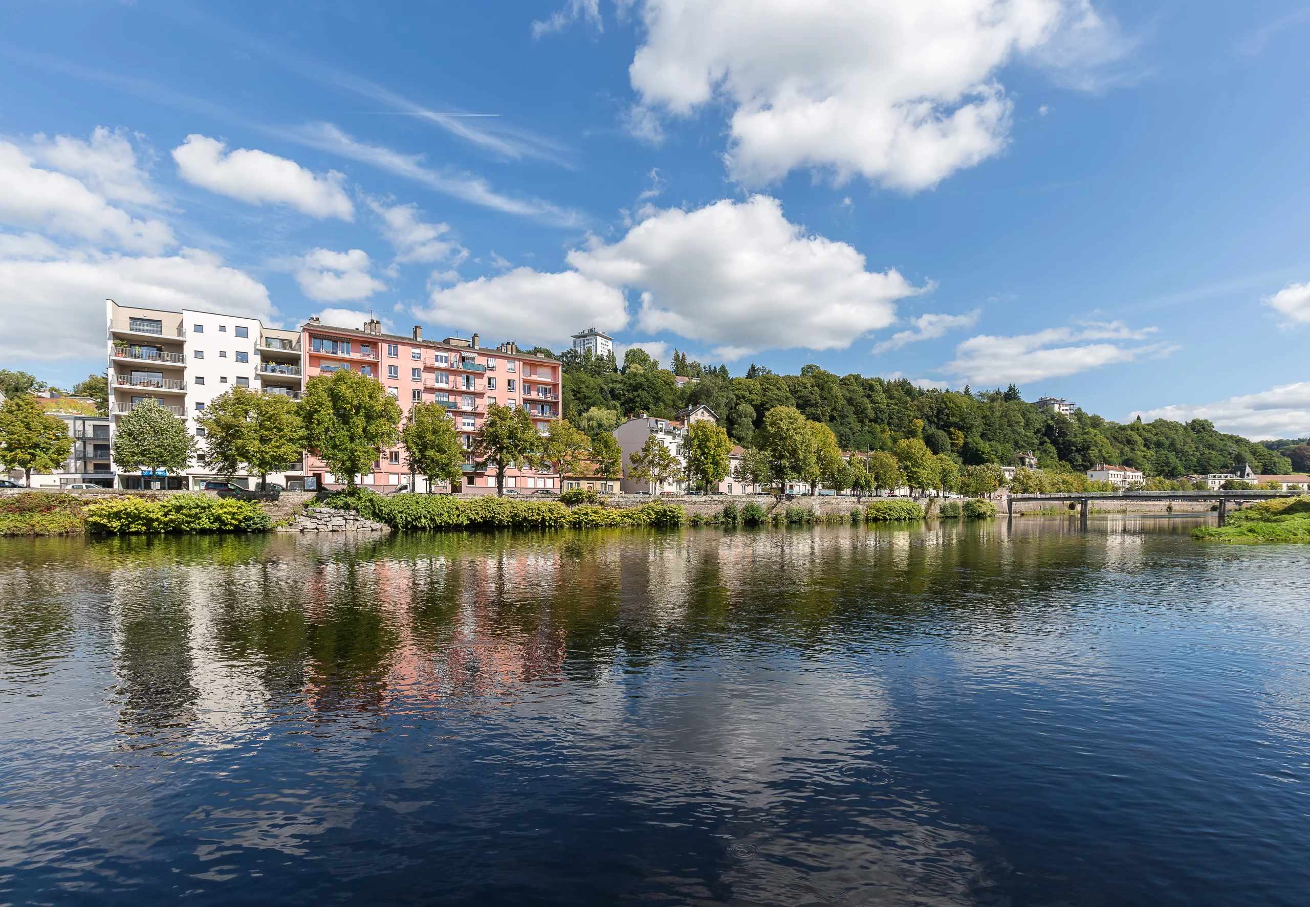 Rivière avec bâtiments et ciel bleu en arrière-plan.