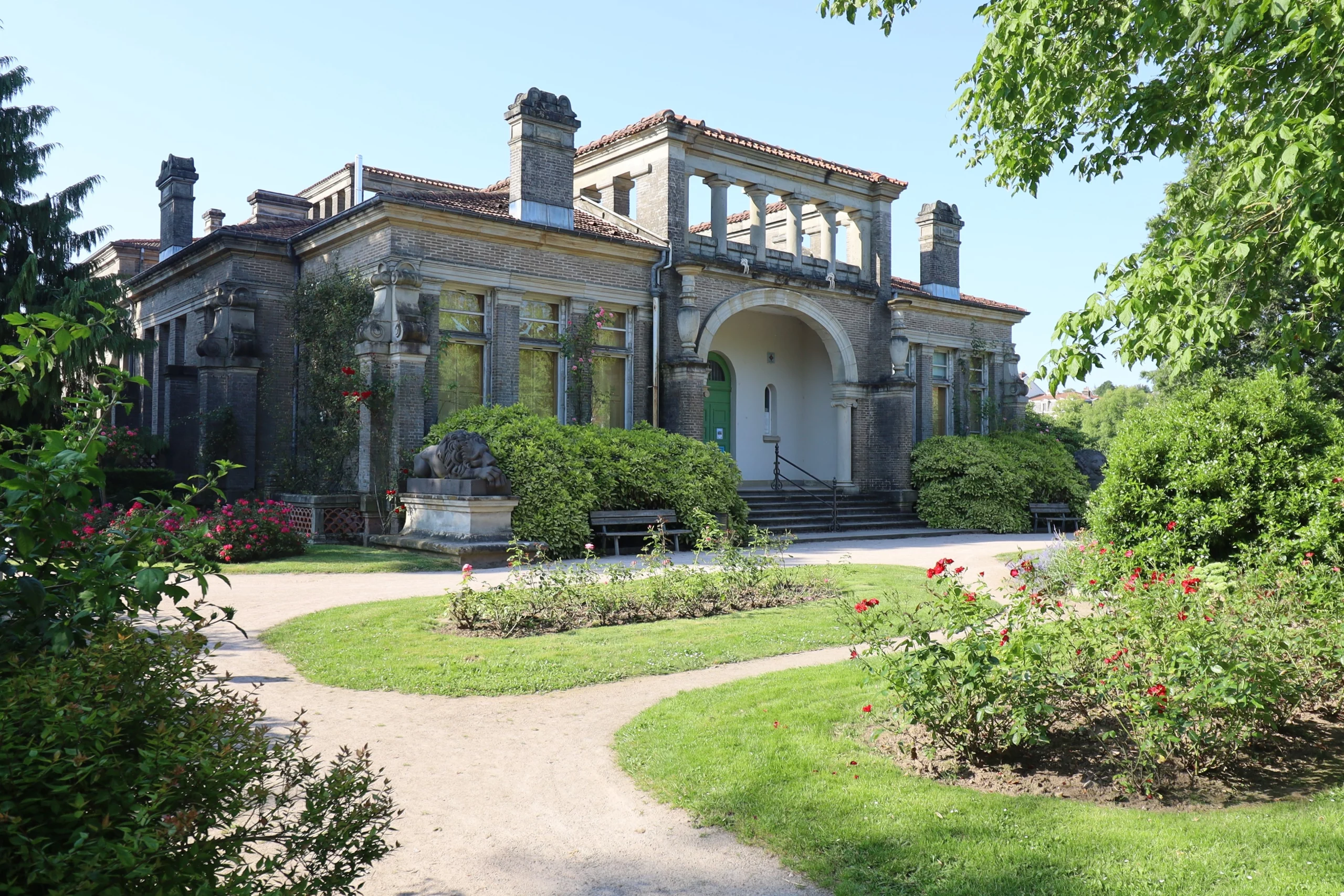 Bâtiment historique avec jardin verdoyant en arrière-plan.