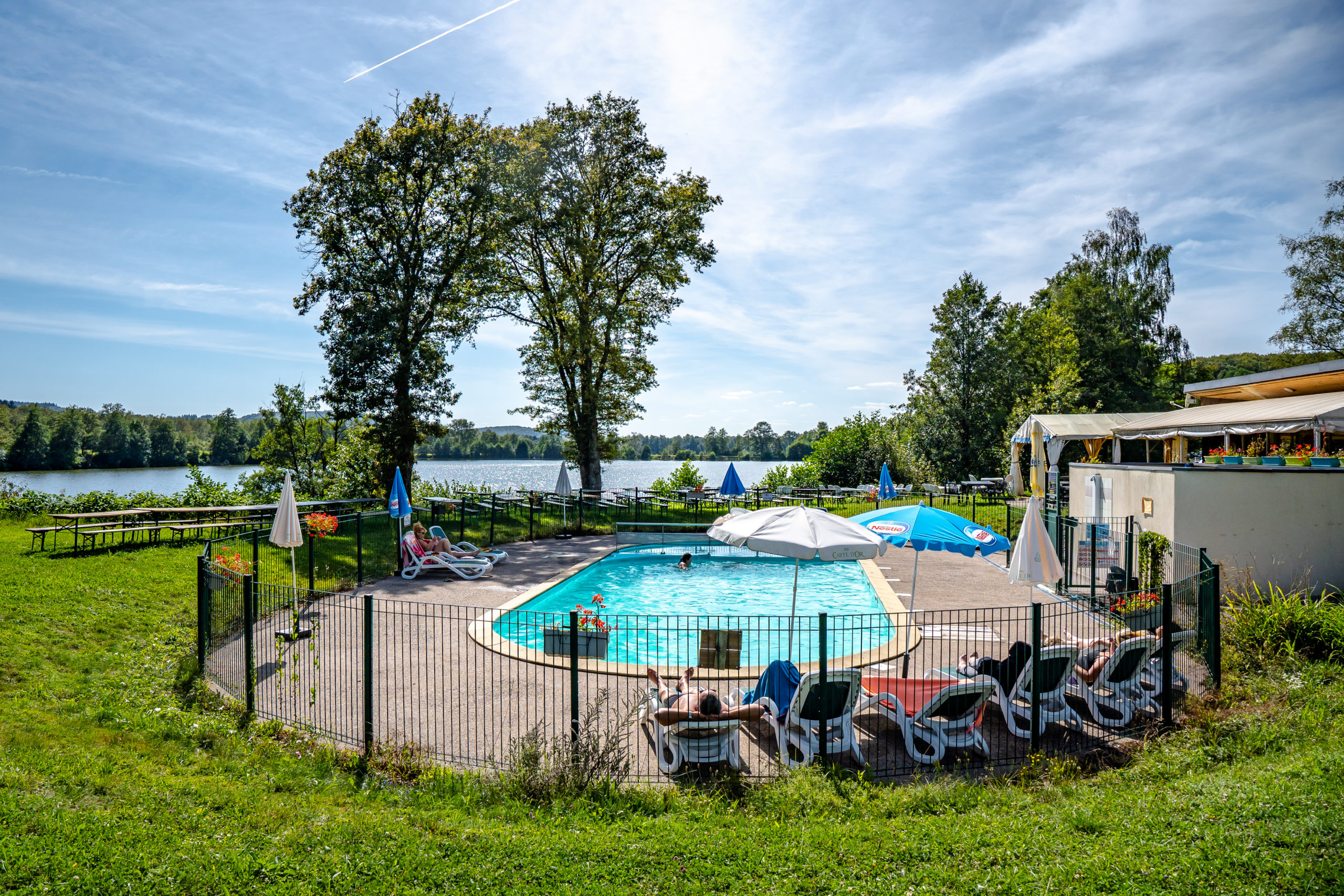 Piscine extérieure avec vue sur le lac et jardin.