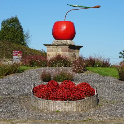Sculpture de cerise géante sur rond-point fleuri.