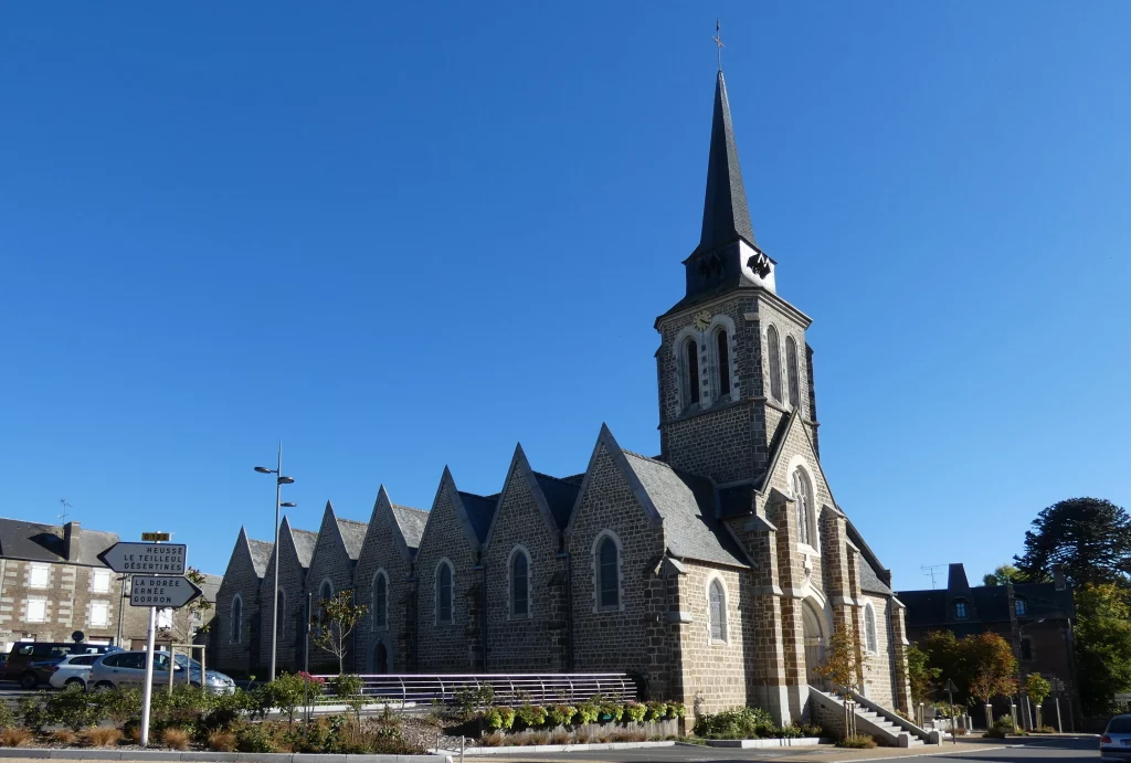 Église en pierre avec clocher sous ciel bleu.