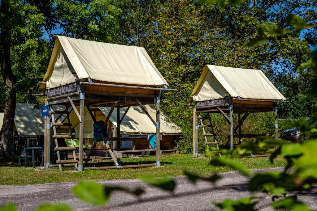 Tentes surélevées dans un camping en forêt.