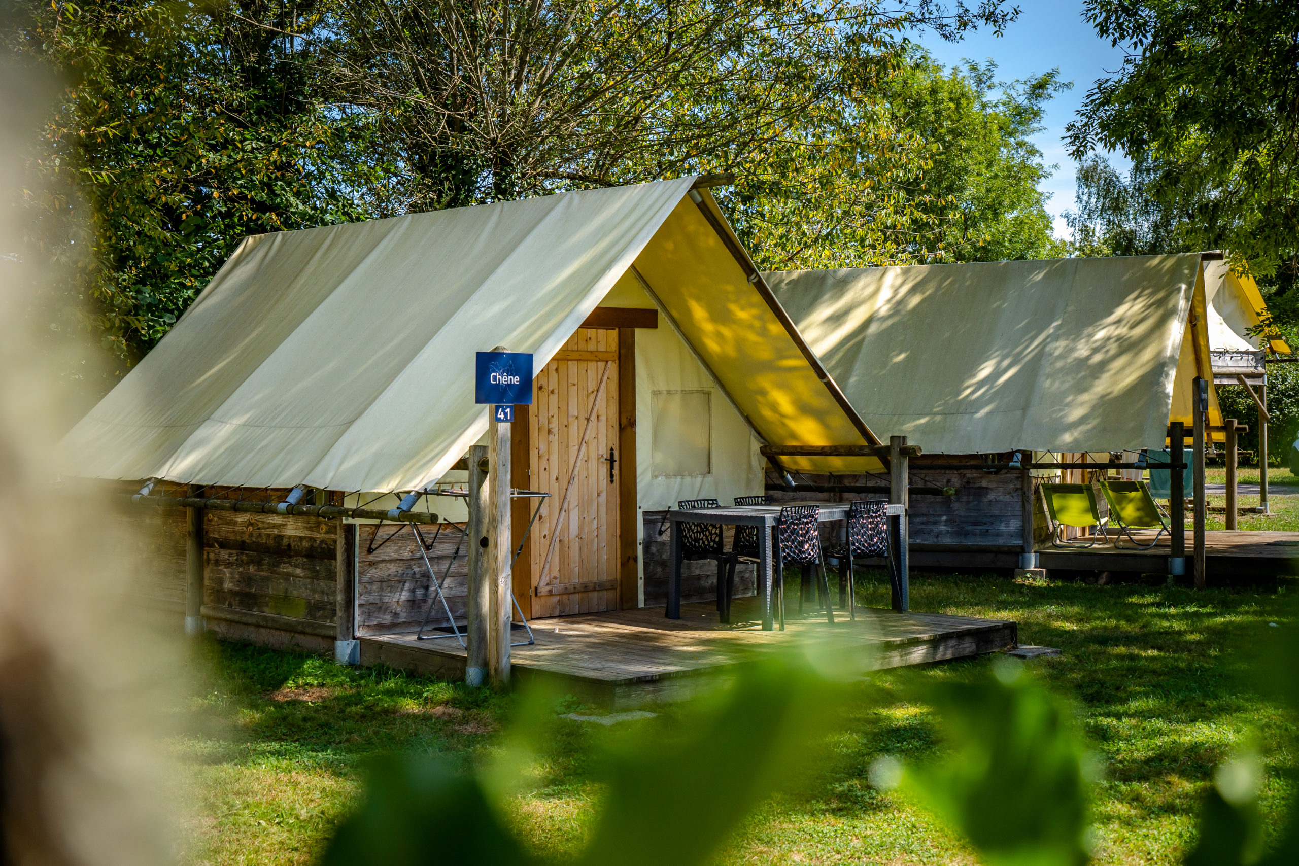 Tente glamping en bois dans un cadre verdoyant.