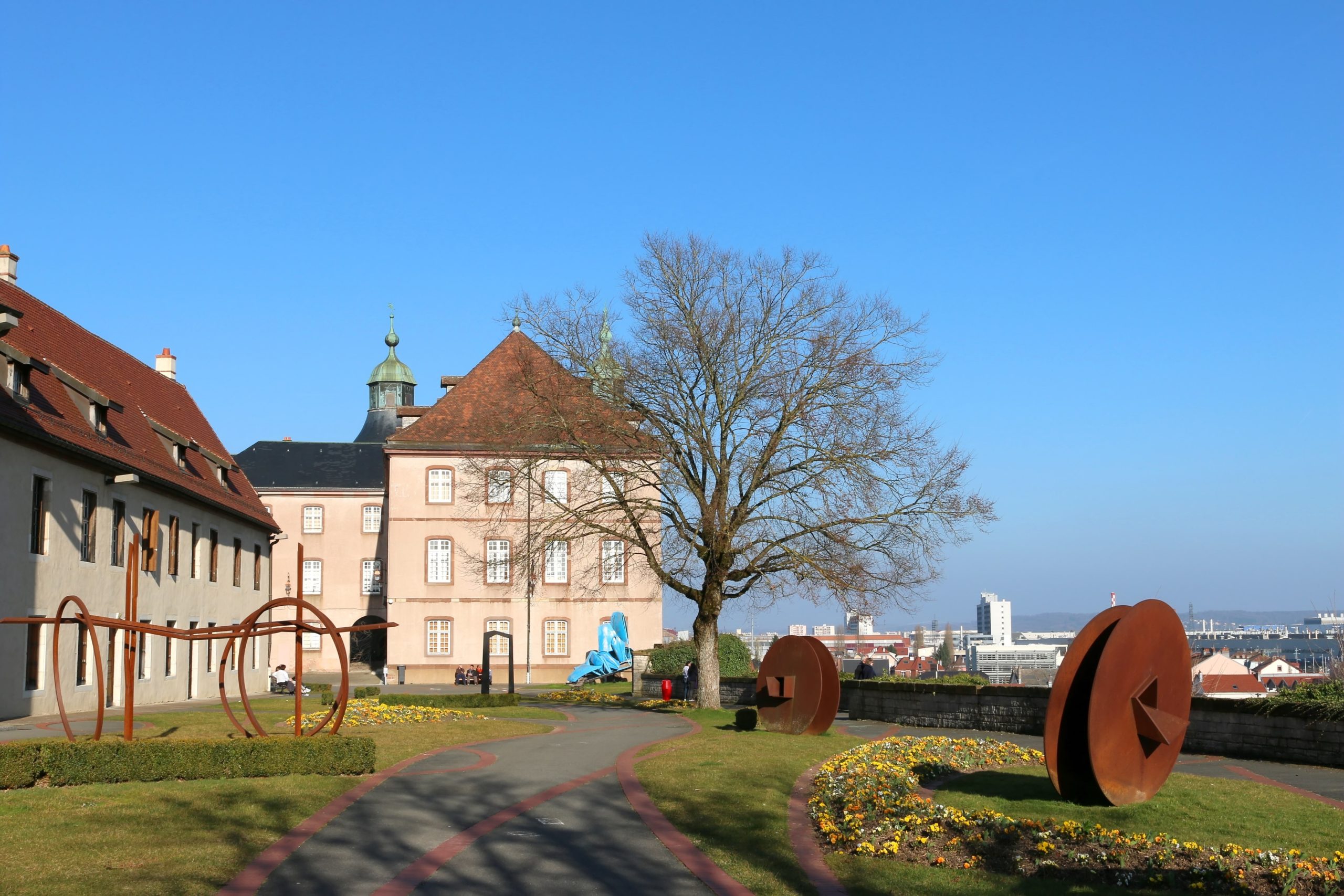 Jardin avec sculptures et bâtiments historiques par temps clair.