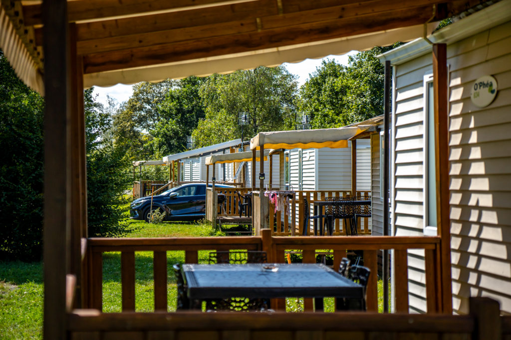 Mobil-homes ensoleillés dans un camping verdoyant.