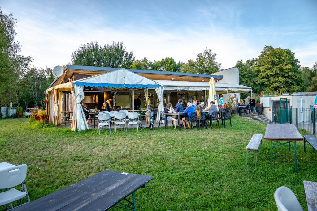 Groupe d'amis mangeant en extérieur, restaurant jardin.