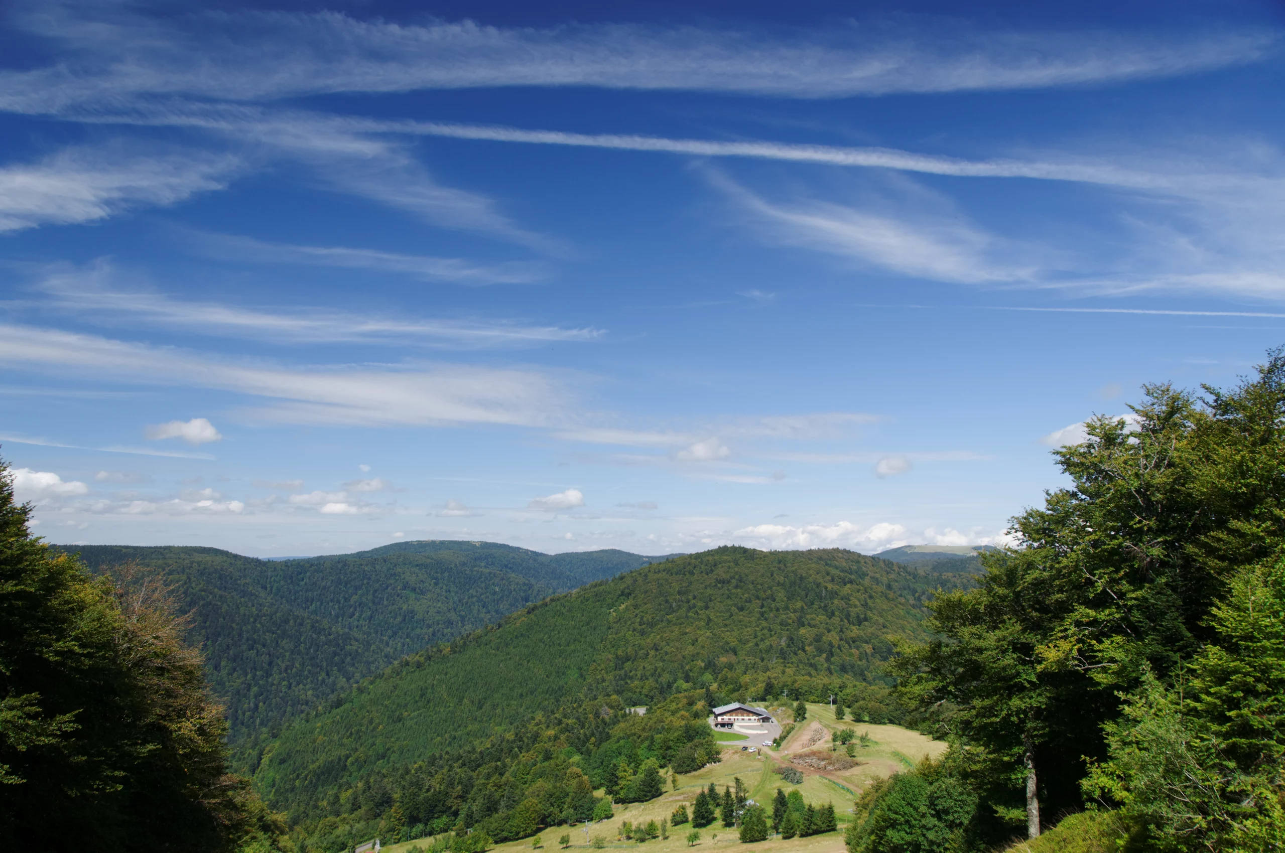 Paysage montagneux ensoleillé avec ciel bleu et nuages.