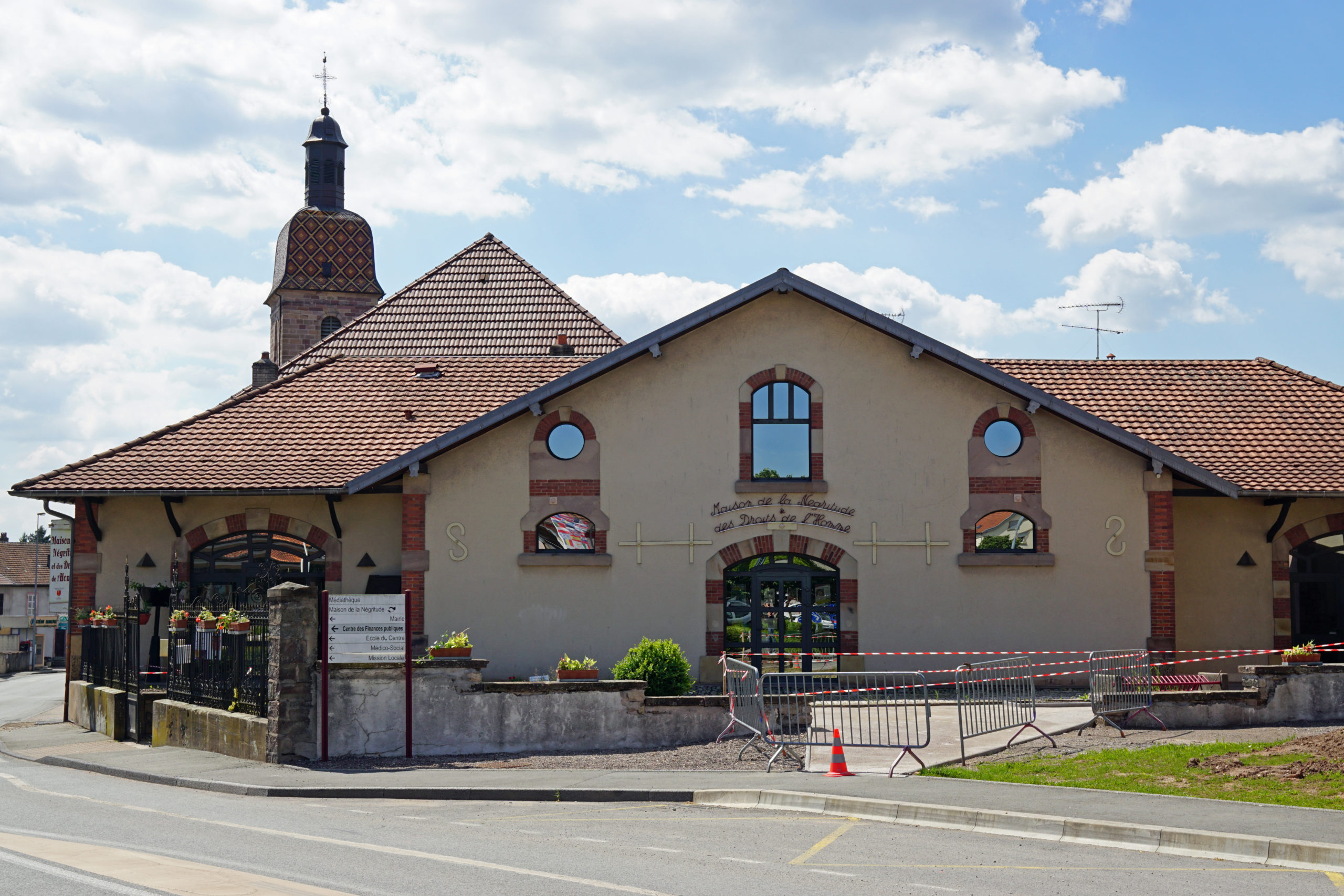Maison traditionnelle avec clocher en arrière-plan.
