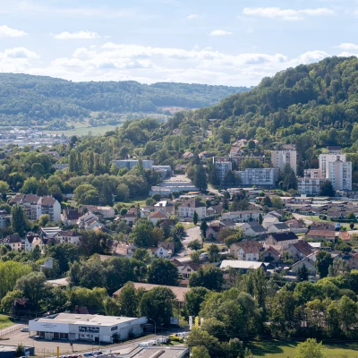Vue aérienne d'une ville avec colline boisée.
